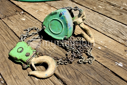 Green block and tackle chain on a wooden deck made from solid sleeper beams.