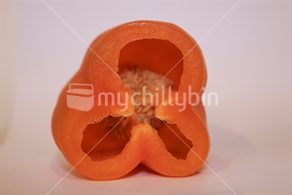 Orange pepper capsicum on white background cut open, focus on cut edge.