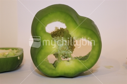 Green pepper capsicum on white background cut open (soft focus on internal seeds).