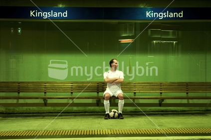 Soccer player waiting at train station, New Zealand