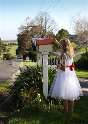 Young girl checking for mail at a rural letterbox. 