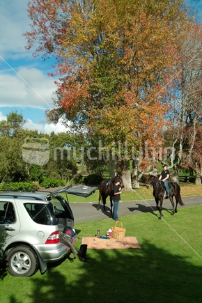 Picnic in Autumn with two horse riders in background