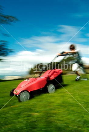 Boy pushing a battery powered lawnmower (artistic motion blur)