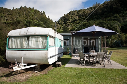 A typical kiwi holiday bach and permanent caravan in a bush setting.