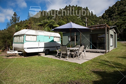 A typical holiday bach and permanent caravan in a bush setting.