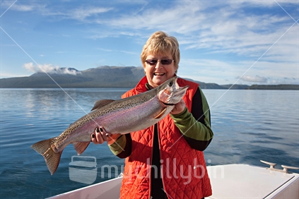 Happy trout fisherwoman on Lake Tarawera with a very large rainbow trout.