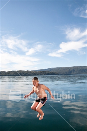 A boy jumping into Lake Tarawera from a boat