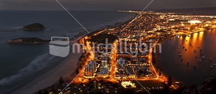 A panoramic shot taken from the top of Mount Maunganui late one evening. The view encompasses areas that include some of the motor camp at the base up past the islands and up along the Mount to Papamoa coastline, extending across the Papamoa Hills and down through the port and Pilot Bay. This is a long 25 second exposure shot, so all moving cars left light trails on the streets below. Highly detailed clear image.