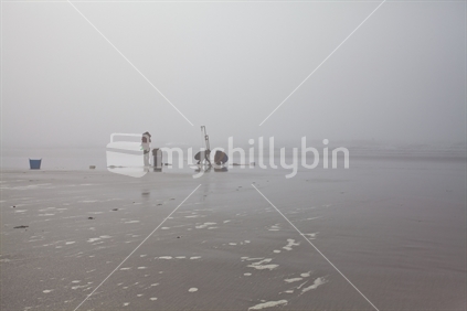Crabbing in the mist on a New Zealand beach at low tide.