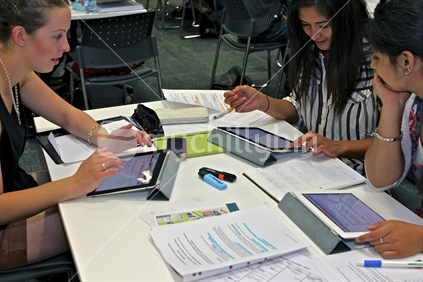 Group of tertiary students using iPads and paper as part of a study tutorial