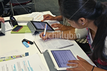 Group of tertiary students using iPads and paper as part of a study tutorial