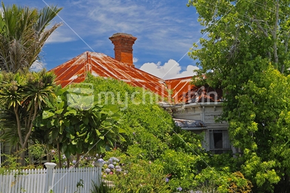 Villa house with rusty roof in overgrown garden