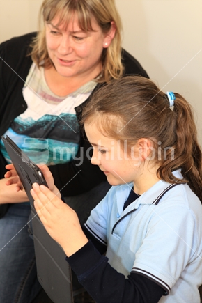 Girl school student working on a computer with teacher or Mum