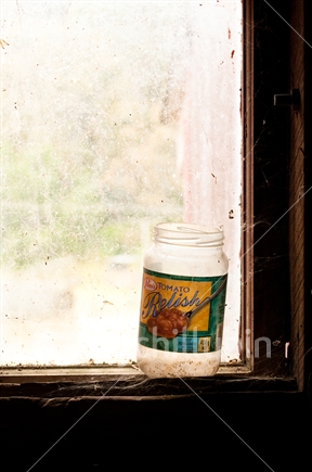 Discarded Pam's Tomato Relish jar sitting on window ledge in old barn