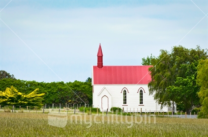 Old red and white church in rural setting, side view