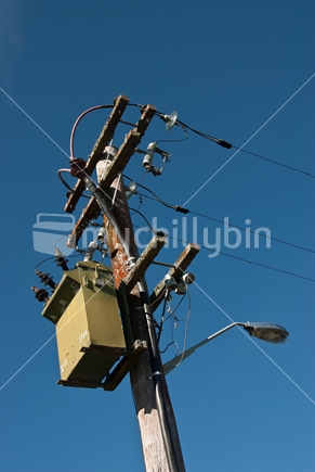 Electricity power pole, transformer and lines, with streetlight, showing details.