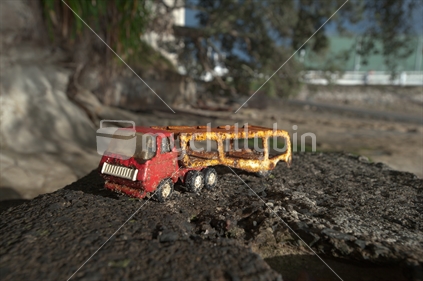 An old toy truck on a beach.
