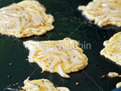 Whitebait fritters on a barbecue hot plate.