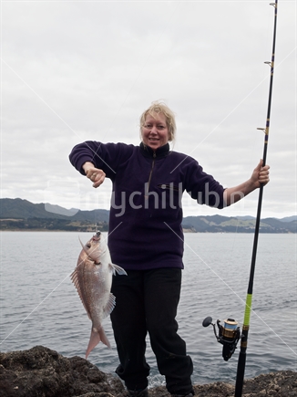A woman angler shows off a good snapper; caught from rocks at East Cape, North Island, New Zealand. 