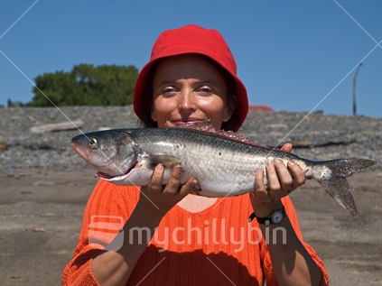 A woman poses with a freshly caught kahawai at Haumoana Beach, Hawke's Bay, New Zealand.