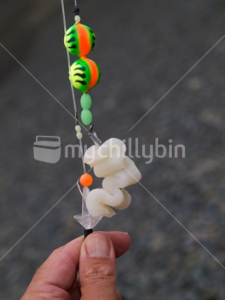 A surfcasting rig baited with squid, decorated with floats and beads, and clipped to a bait clip for casting.  