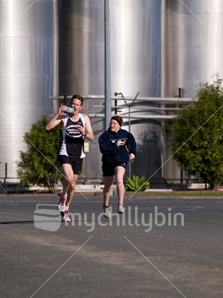 Road race at Gisborne with winery in background. Daughter giving water bottle to father. 

