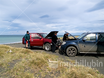 Vehicle owner with a flat battery at a Cape Palliser beach gets assistance from passersby. 