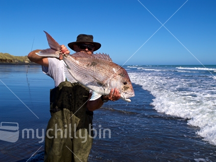 Man showing large snapper caught while surfcasting