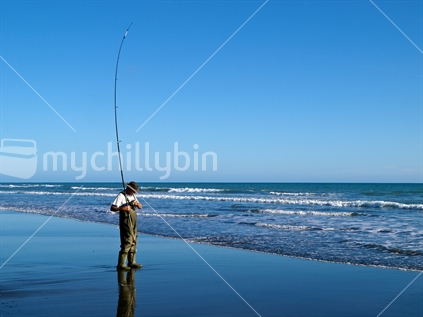 Man checking his surfcasting rod to see if he's hooked a fish