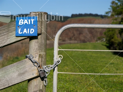 Sign and padlock indicating that poison bait has been laid alongside a river. 