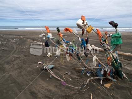 Collected beach rubbish displayed temporarily on driftwood at Sunset Beach, Port Waikato, New Zealand