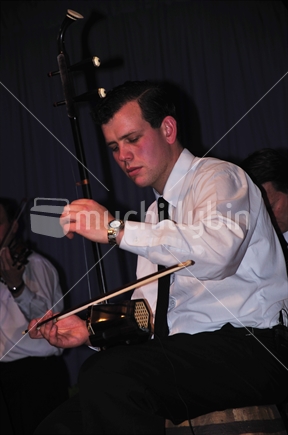Detail of a New Zealand man playing a chinese violin, the urhu, in a live performance
