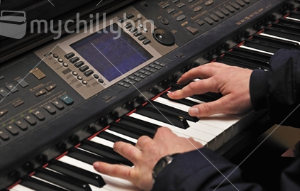 Detail of a man playing an electronic piano in a live performance