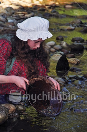 Schoolgirl dressed in period costume panning for gold at Shantytown, Westland, on a school outing to learn about the gold rushes.