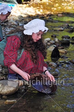 Schoolgirl dressed in period costume panning for gold at Shantytown, Westland, on a school outing to learn about the gold rushes.