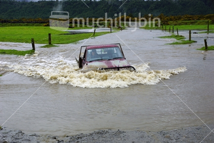 Farmer driving his ute through a flooded paddock in Westland
