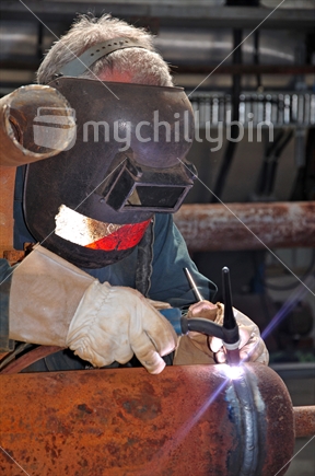 A man welding up steam pipes for a manufacturing plant