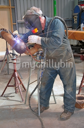 A man welding up steam pipes for a manufacturing plant