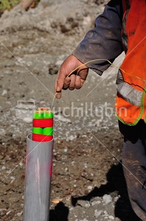 Man lowering an explosive charge into a three metre hole for a seismic reflective survey