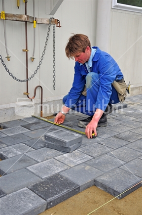 Builder setting out paving stones for a pathway at a construction site in Westland