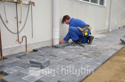 Builder setting out paving stones for a pathway at a construction site in Westland