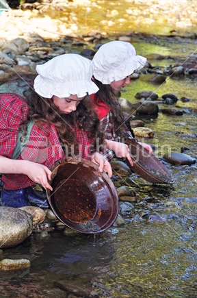 Girls in 19th century costume, panning for gold at Shantytown, on an educational field trip.