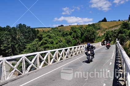 Motorcyclist catches a glimpse of Rakaia Gorge as he crosses the bridge, Canterbury, South Island, New Zealand.