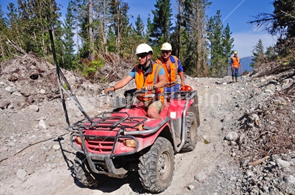 Men travel in an all terrain vehicle while setting out cables for a seismic reflective survey