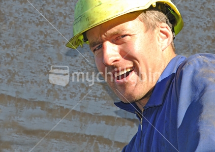 Happy New Zealand worker in overalls and hard hat.