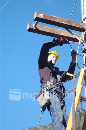 Electrician secures wires on power pole
