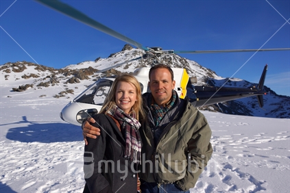 Tourists pose before their chopper on the neve of the Franz Josef Glacier during a helicopter visit in the Southern Alps