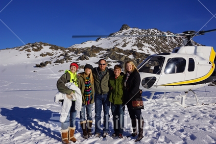 Tourists pose before their chopper on the neve of the Franz Josef Glacier during a helicopter visit in the Southern Alps