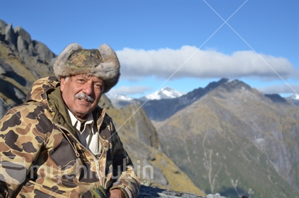 Mature man in camouflage gear poses in the Southern Alps