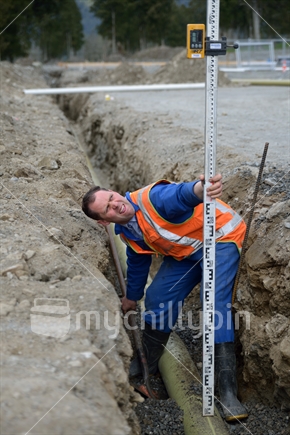 A tradesman checks the depth of a new stormwater drain, to get the correct fall.